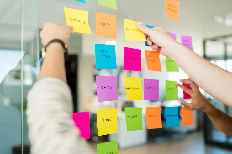 Equipo organizando ideas con notas adhesivas de colores en una pared de cristal