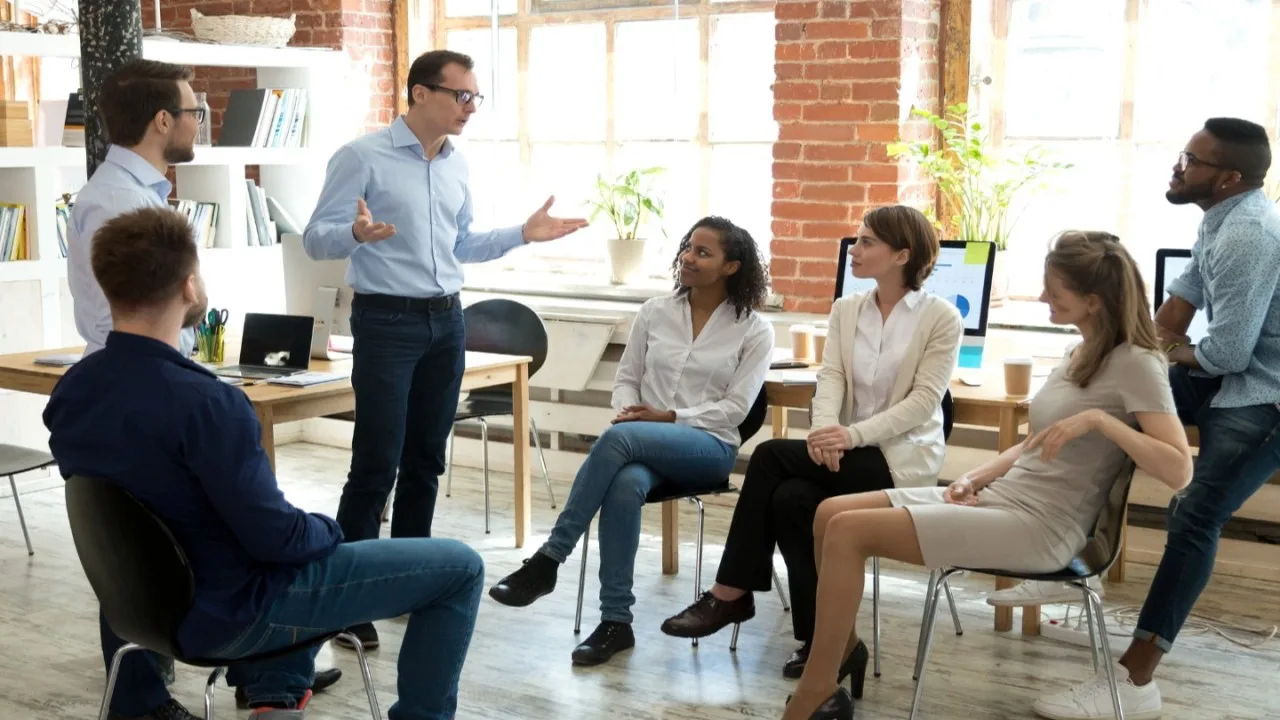 Líder conversando con su equipo en una oficina luminosa